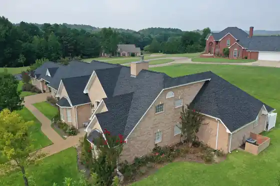 Oblique aerial view of a brick home and its neighbours on rolling lawn