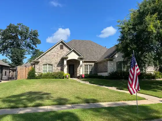 Brick home with a US flag in the yard under a blue sky