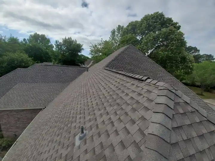 New architectural shingle courses running to a hip under an open sky