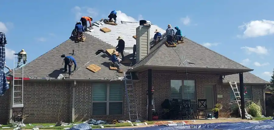 A BXC crew of more than eight roofers working one roof together, ladders up, blue sky