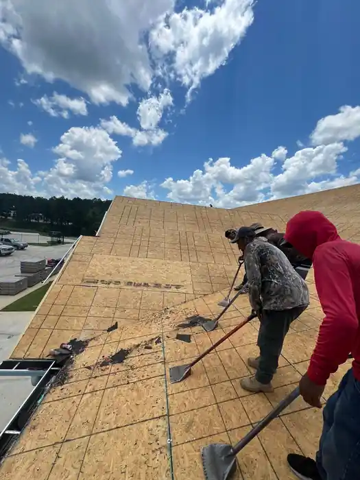 Crew sweeping bare roof decking before underlayment goes on