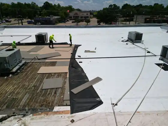 White TPO membrane being installed on a commercial flat roof by a crew in hi-vis
