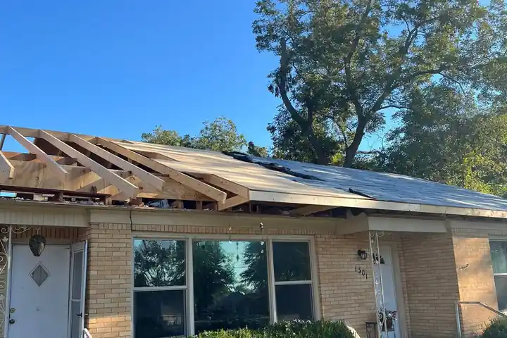 A storm-damaged roof opened to the rafters on a brick ranch house