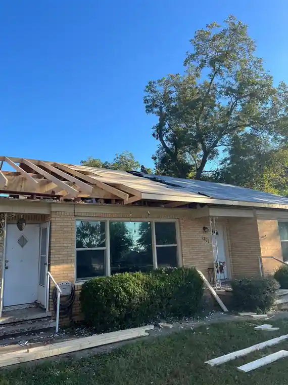 Storm-damaged roof opened to the rafters on a brick ranch house