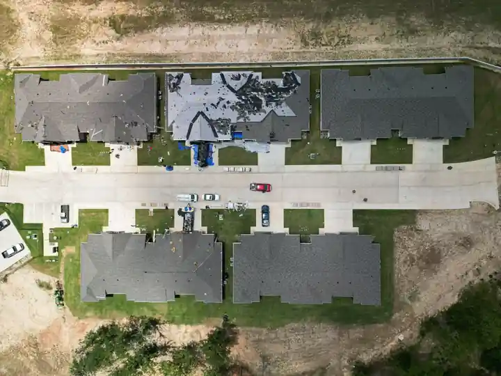 Overhead drone view of a small subdivision of townhomes with matching new roofs