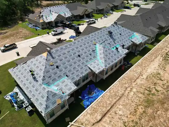 Aerial view of a townhome block mid re-roof, underlayment beside new shingles