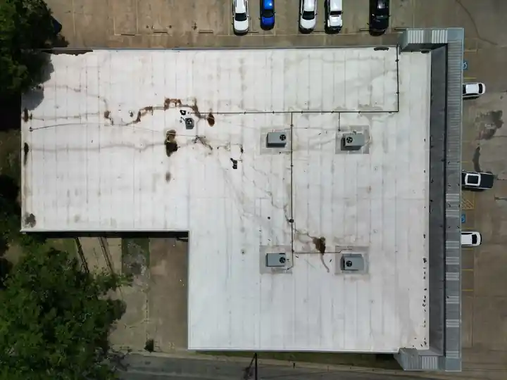 Overhead drone view of a finished white TPO commercial roof with rooftop units