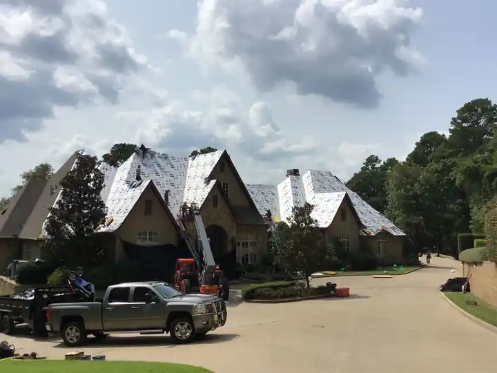 Large two-storey home dried in with white synthetic underlayment and a crew pickup in the drive